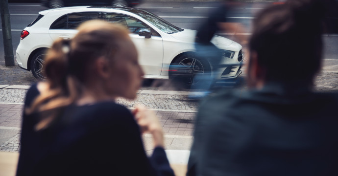 Zwei Personen und ein Mercedes-Benz Fahrzeug im Hintergrund