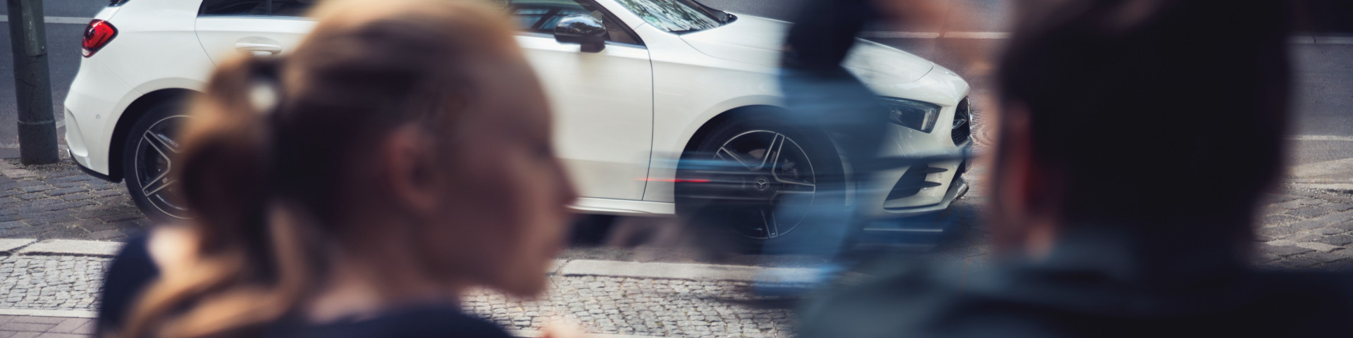 Two people and a Mercedes-Benz car in the background