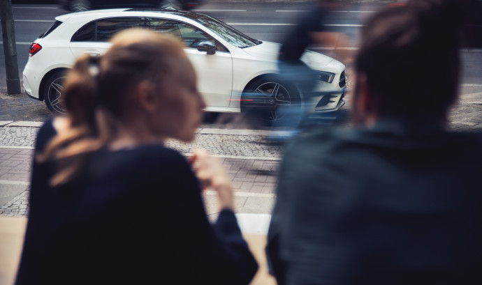 Two people and a Mercedes-Benz car in the background